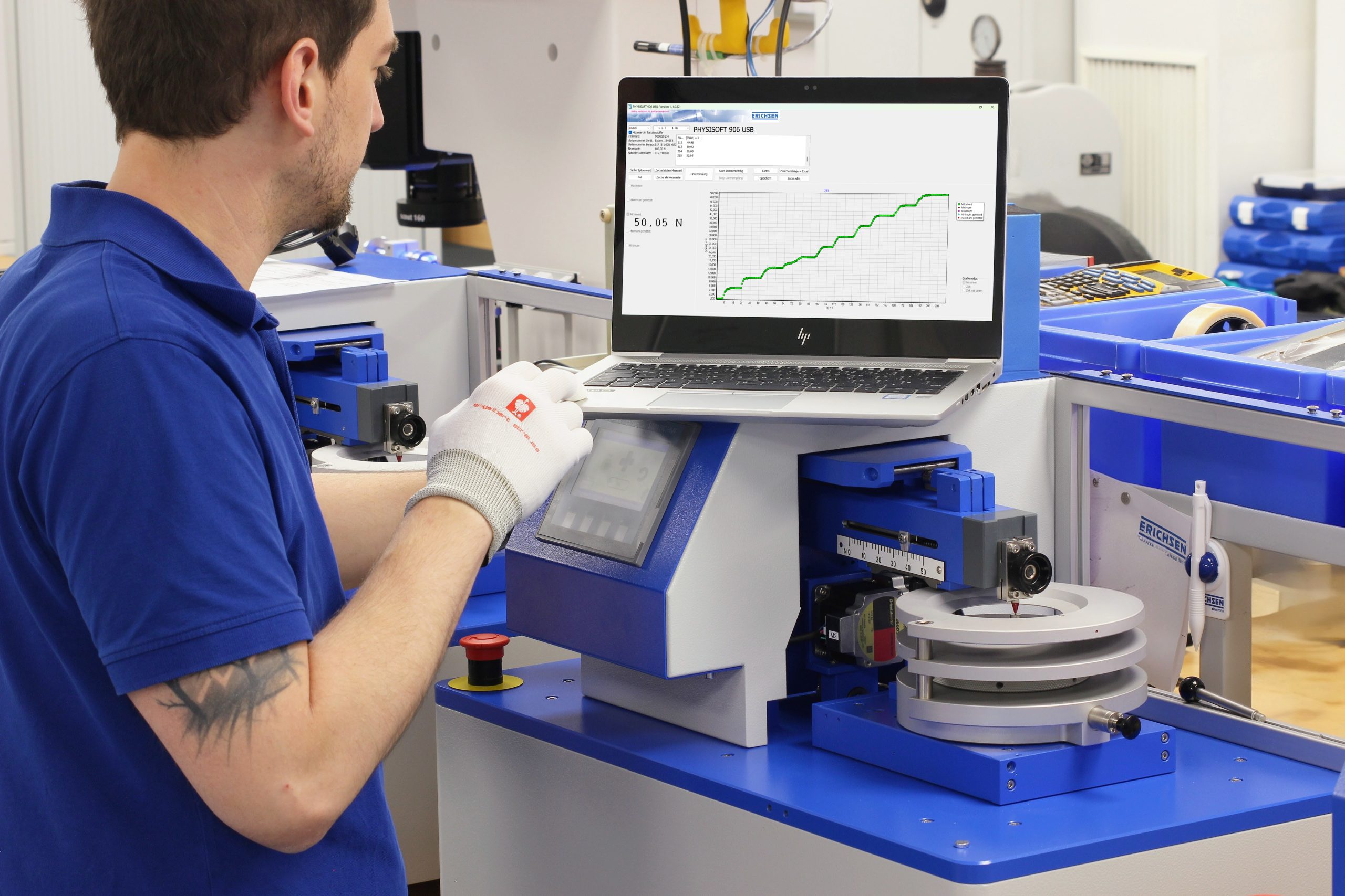 An engineering technician uses blue and grey Erichsen test instruments in a clean workshop area